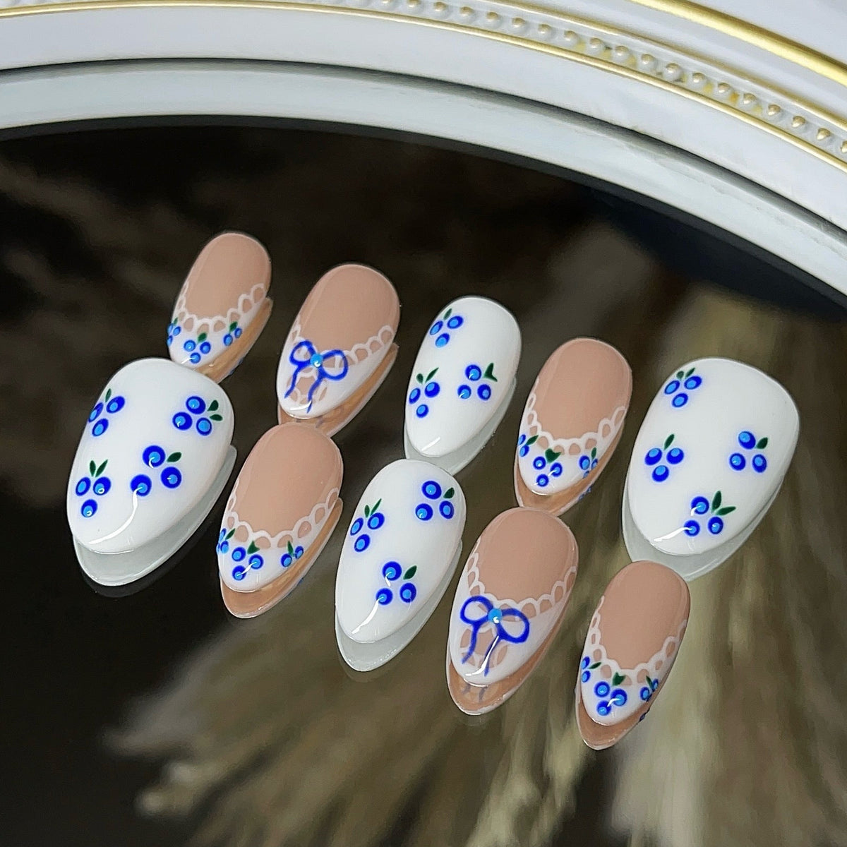 10 press-on nails with white french, scallop trim, blue blueberry designs, and blue bow.
